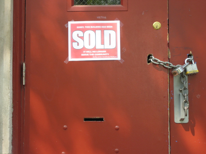 Photo of padlocked door with sign taped to the door reading "Sorry this building has been sold. It will no longer serve the community."